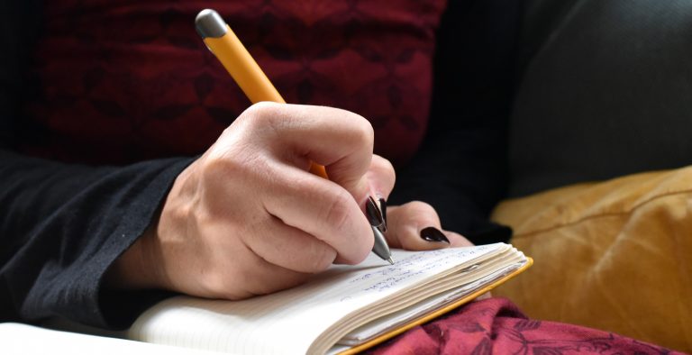 Eine in eine Kladde schreibende Hand mit Kugelschreiber