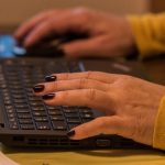 Schreibende Frauenhände auf einer Tastatur