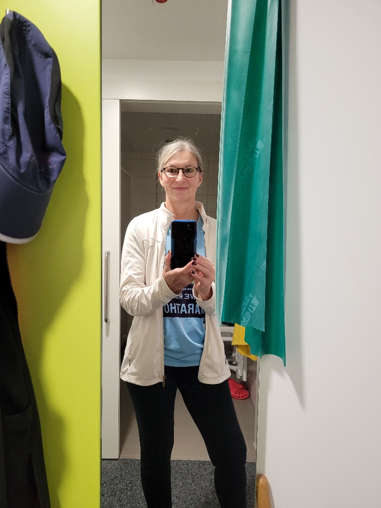 Eine Frau in Sportklamotten steht vor dem Spiegel, an dem ein Teraband hängt.