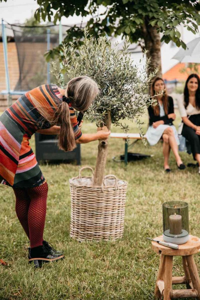 Die Freie Rednerin befestigt ein Kärtchen an einem Olivenbaum