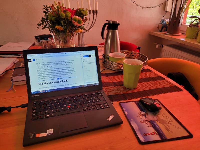 Tisch mit Laptop und Kaffee- sowie Teebecher