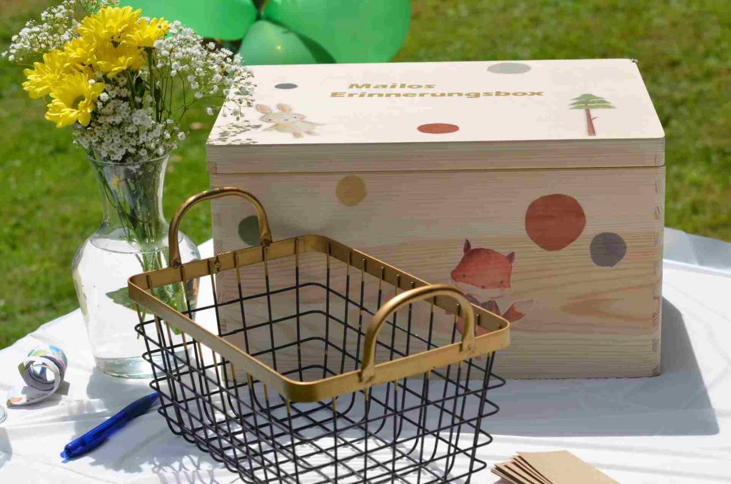 Holzkist mit Kinderbildern bedruckt davor ein offener Drahtkorb