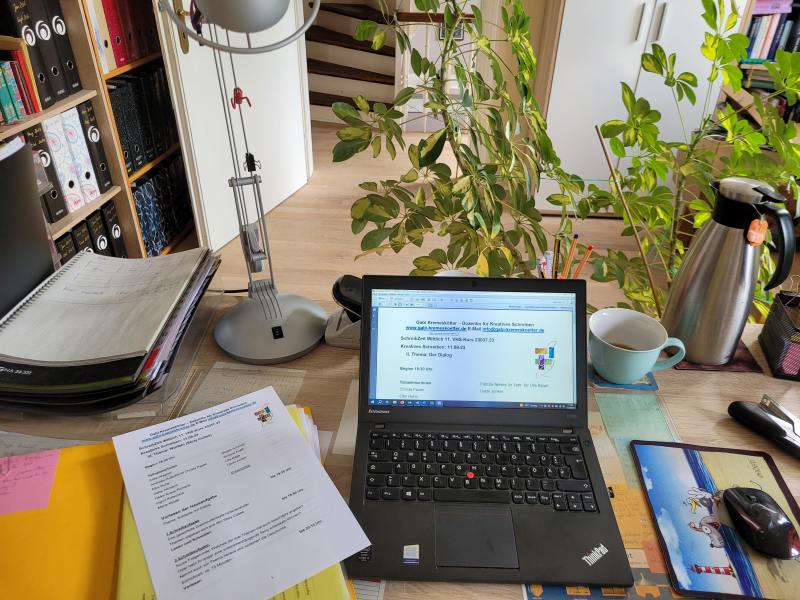 Ein Schreibtisch mit Laptop, Thermoskanne und Papieren