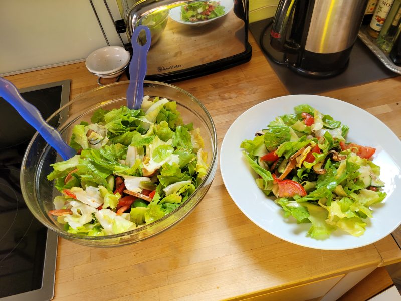 Eine Glasschüssel und ein großer weißer Teller voll mit gemischtem Salat.