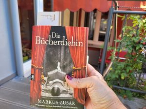 Das Buch "Die Bücherdiebin" in der Hand einer Frau auf Terrasse