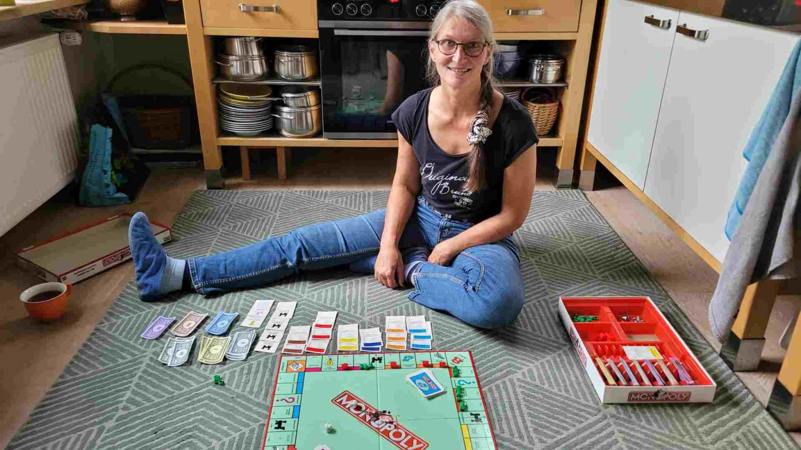 Frau auf Teppich in der Küche vor Monopoly-Spiel