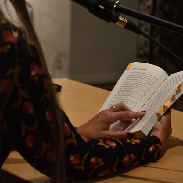 Eine Frau hält ein aufgeschlagenes Buch, in dem Textstellen markiert sind.
