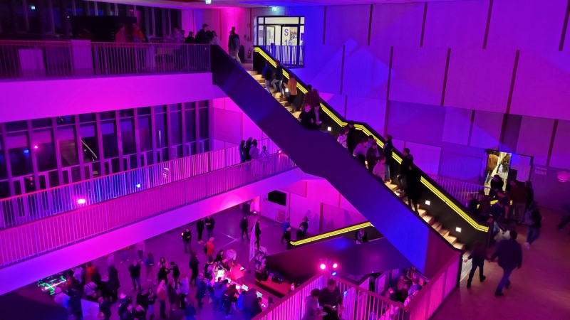 Offener Raum mit Treppen über mehrere Stockwerke der RWTH Aachen in lila-blauer Beleuchtung während der Wissenschaftsnacht 2023
