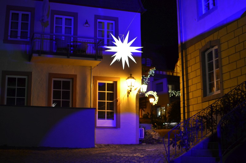 Großer Weihnachtsstern in blau-golden illuminierter Altstadtgasse