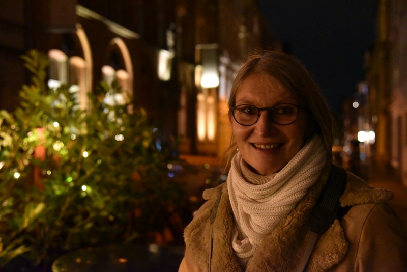 Frau in weihnachtlich erleuchteter Straße lächelt in die Kamera.