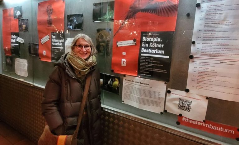Frau im Wintermantel steht vor dem Schaufenster des Theaters im Bautum in Köln