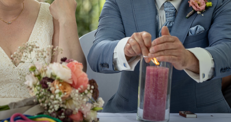 Bräutigam zündet eine rosa Kerze an.