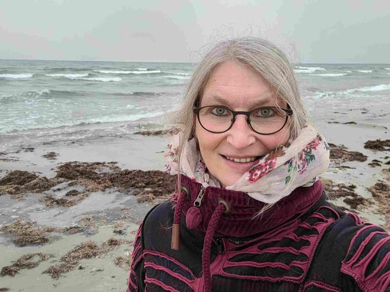 Selfie einer Frau am Ostseestrand mit Schal und Jacke