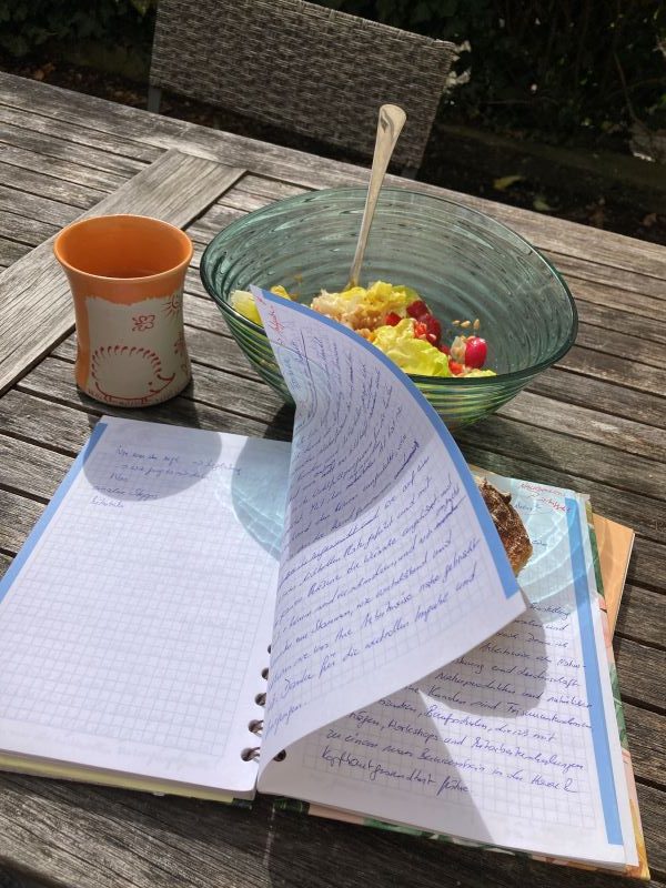 Notizblock auf einem Tisch im Freien bei Kaffee und Müsli