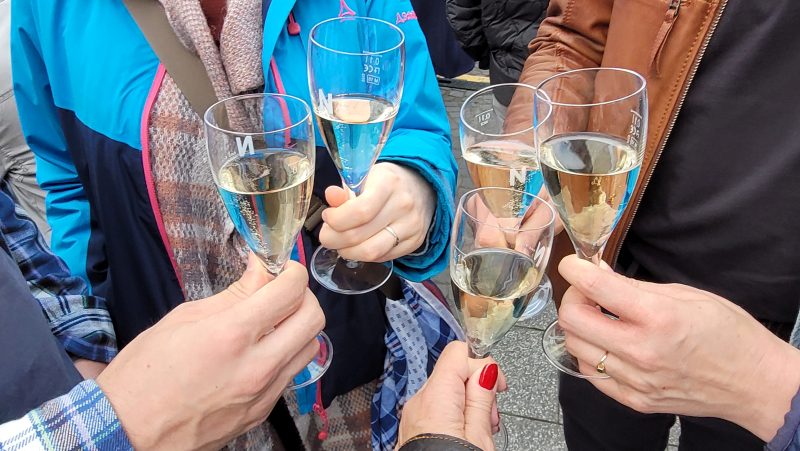 Fünf Personen stoßen mit Secco an, zu sehen sind nur die Gläser mit Händen