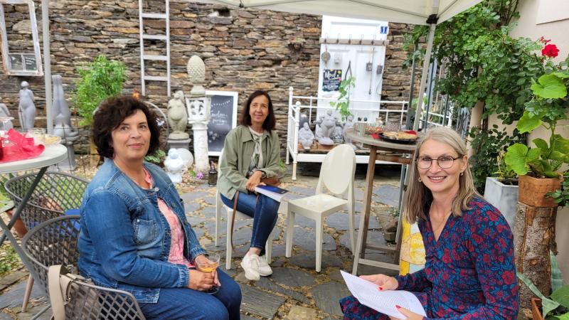 Drei Frauen unter einem Pavillon sitzend schauen in die Kamera
