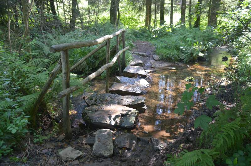 Brücke aus Felssteinen mit Holzhandlauf über Bachlauf bei Börfink