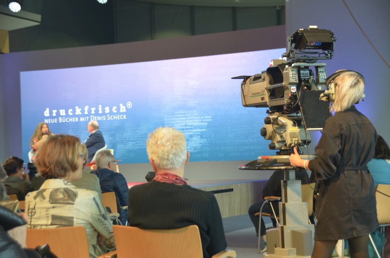 Kamerafrau im Vordergrund bei der Live-Übertragung eines Programmpunkts der Literaturbühne von ARD, ZDF und 3Sat.