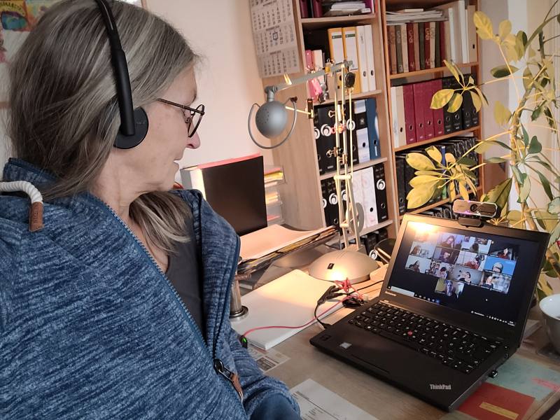 Frau mit Headset vor ihrem Laptop bei einem Online-Meeting