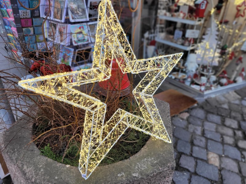 Leuchtender Stern vor einem weihnachtlich geschmückten Schaufenster