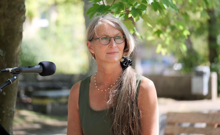 Frau mit langem Zopf schaut nachdenklich zur Seite