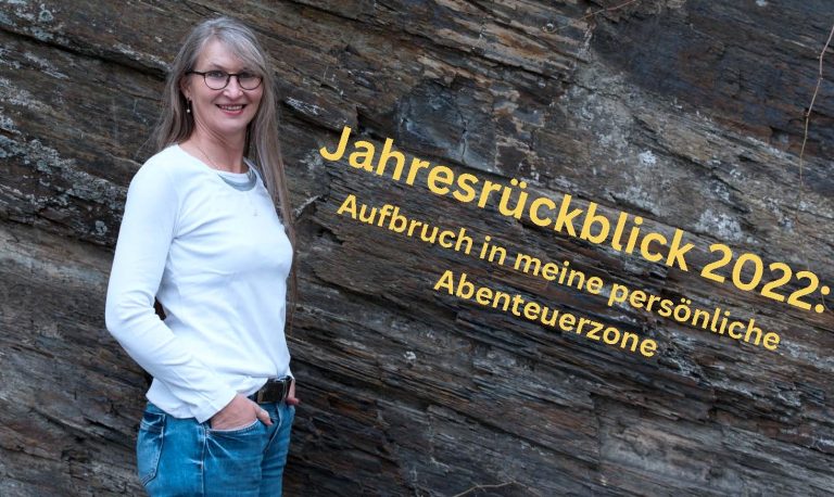 Eine Frau steht vor einer Schieferwand und lächelt in die Kamera