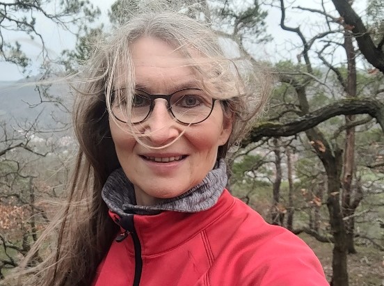 Eine Frau mit verwehten Haaren lächelt in die Kamera