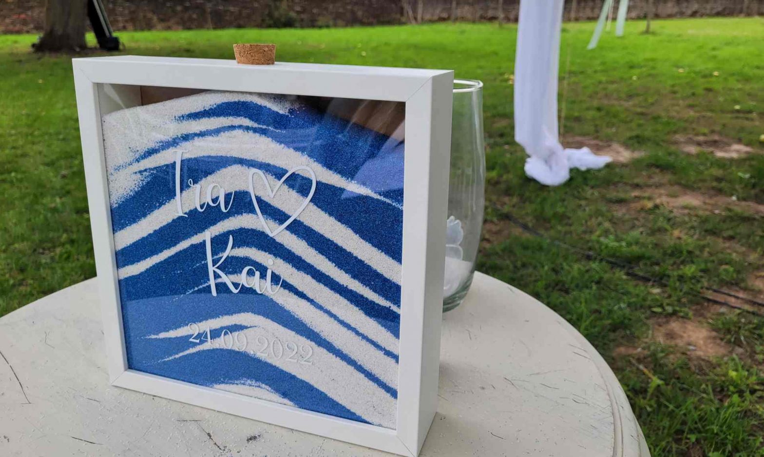 Bilderrahmen mit weiß- blauem Sand in Schichten gefüllt