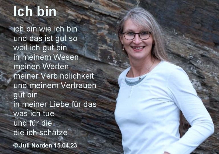 Frau ,mit langen Haaren lächelt in die Kamera vor Schieferwand
