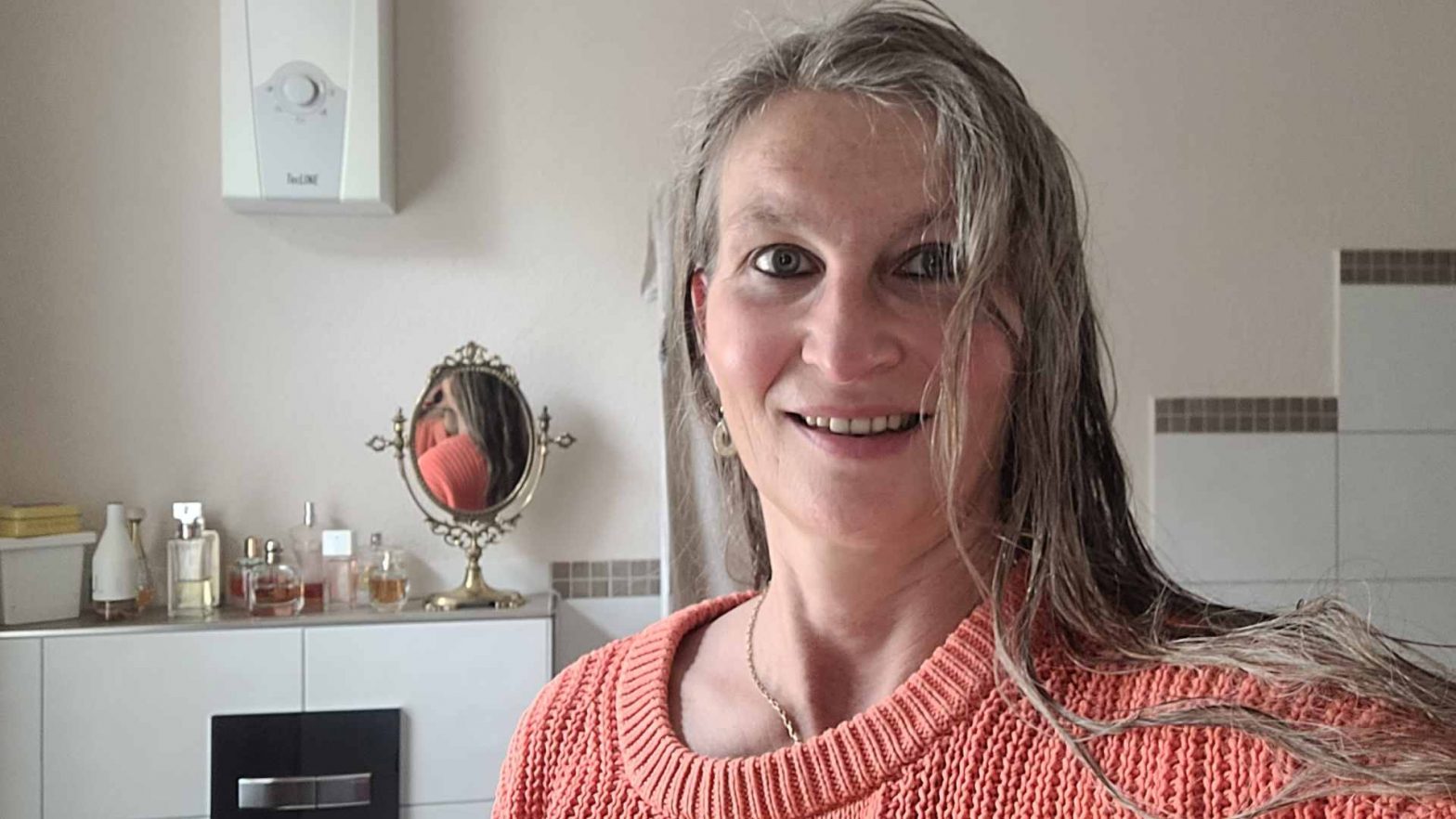 Frau vor Spiegel mit langen nassen Haaren