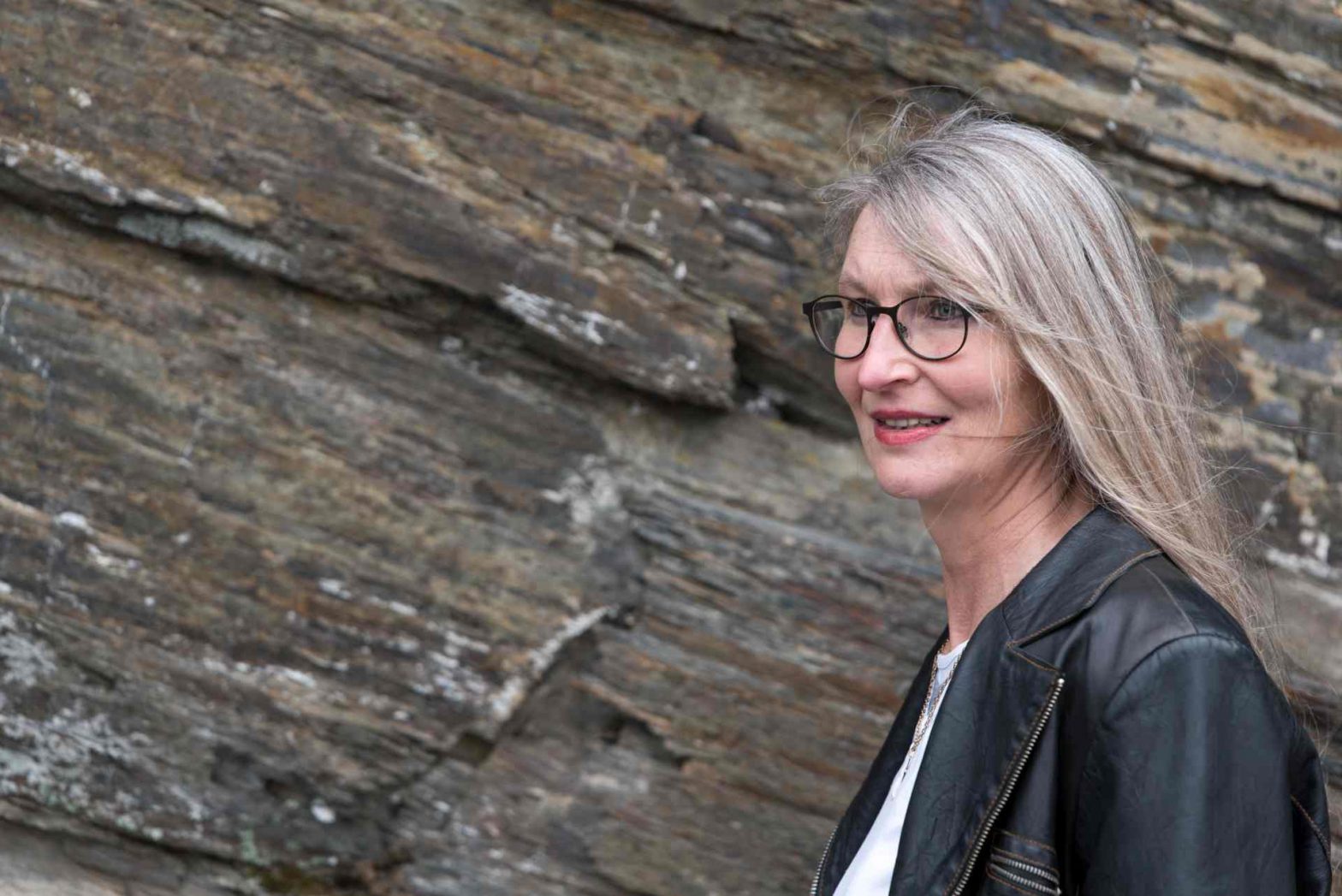 Frau mit langen Haaren und Brille vor Schieferwand