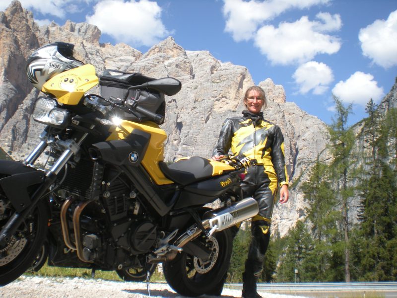 Frau in Lederkombi mit ihrem Motorrad in den Dolomiten