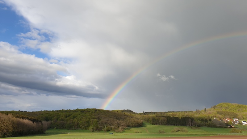 Ein Regenbogen vor Gewitterhimmel über freiem Feld