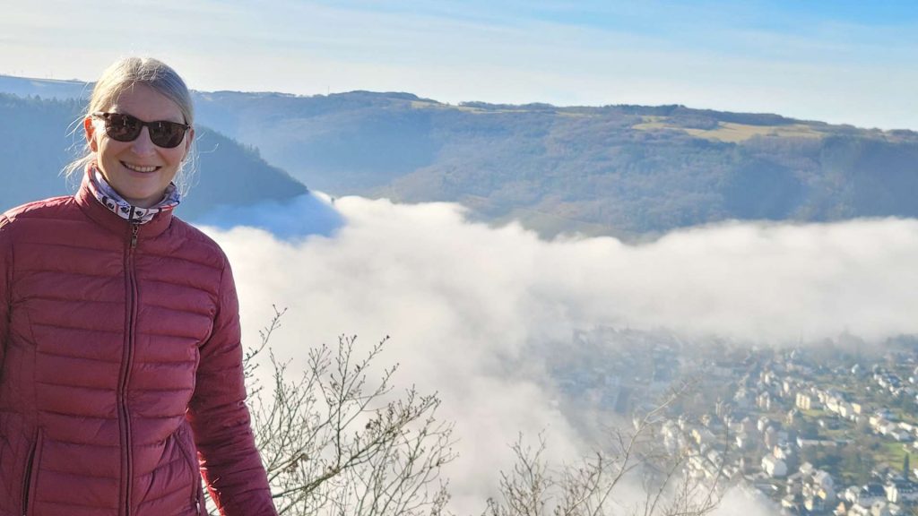 Nebel an der Mosel, eine Wanderin freut sich oberhalb des Flusses über die Sonne