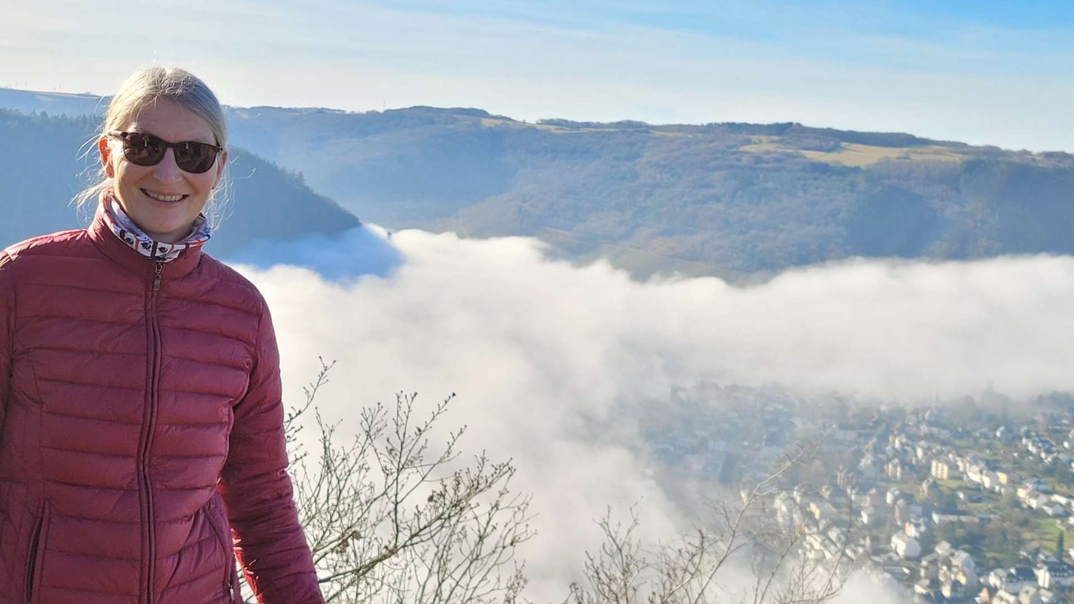 Nebel an der Mosel, eine Wanderin freut sich oberhalb des Flusses über die Sonne