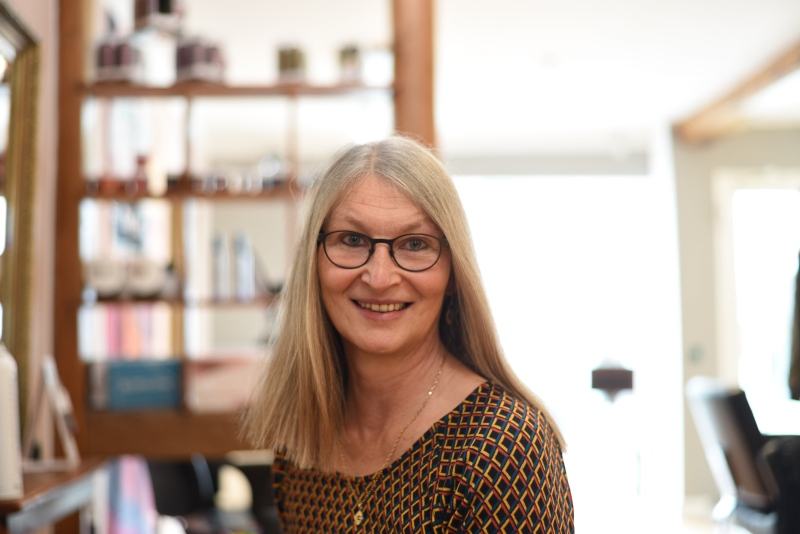 Frau beim Friseur lächelt mit neuer Frisur in die Kamera, sie trägt nun einen sogenannten Longbop.