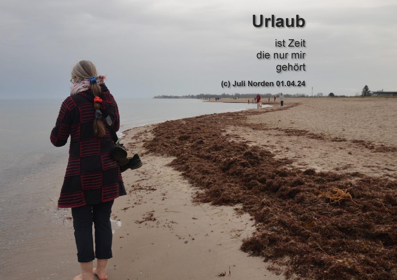 Frau am Ostseestrand, nur von hinten zu sehen, Barfuß mit Jacke und Fotoapparat