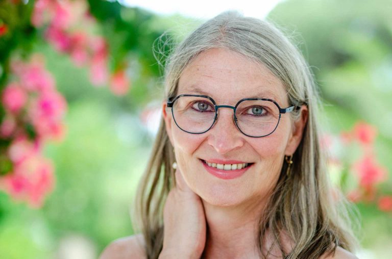 Frau mit Brille und Longbop lächelt in die Kamera