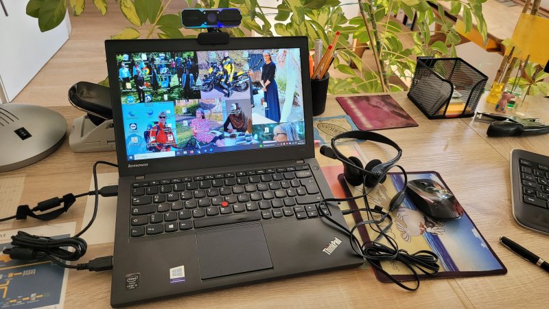 Laptop mit technischen Ergänzungen, Headset, Webcam und Maus auf einem Schreibtisch
