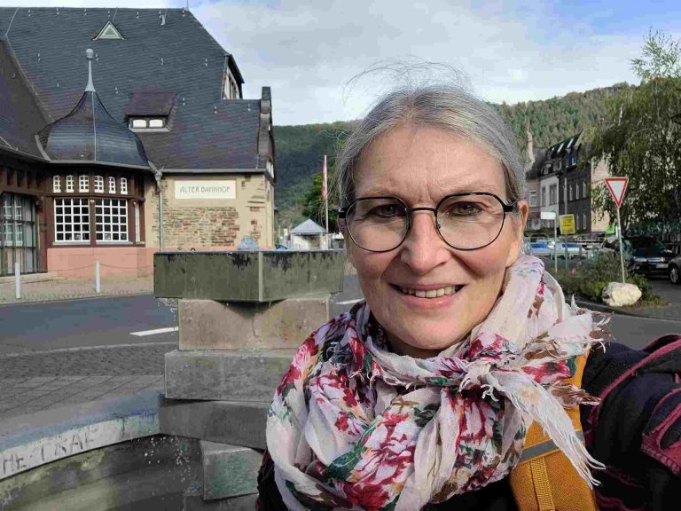 Frau schaut in die Kamera, im Hintergrund der alte Bahnhof von Traben-Trarbach