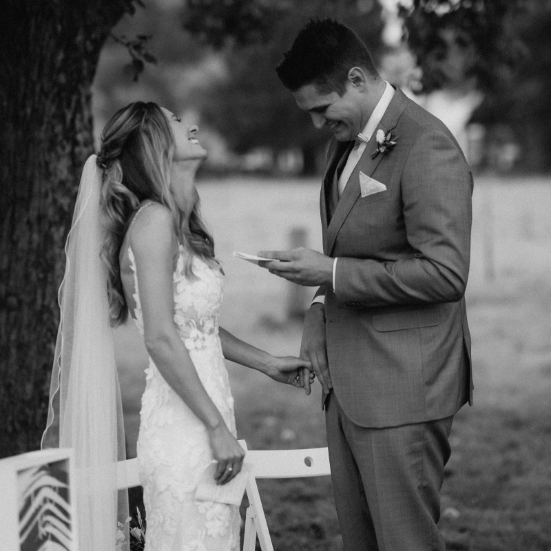 Bräutigam liest Braut sein Liebesversprechen vor, sie lacht glücklich