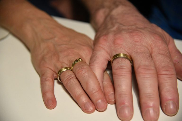 Hände eines Paars mit neuen Ehe-Ringen an den Fingern