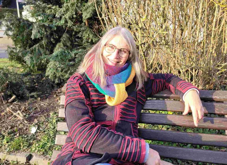 Frau auf Bank lächelt in die Kamera