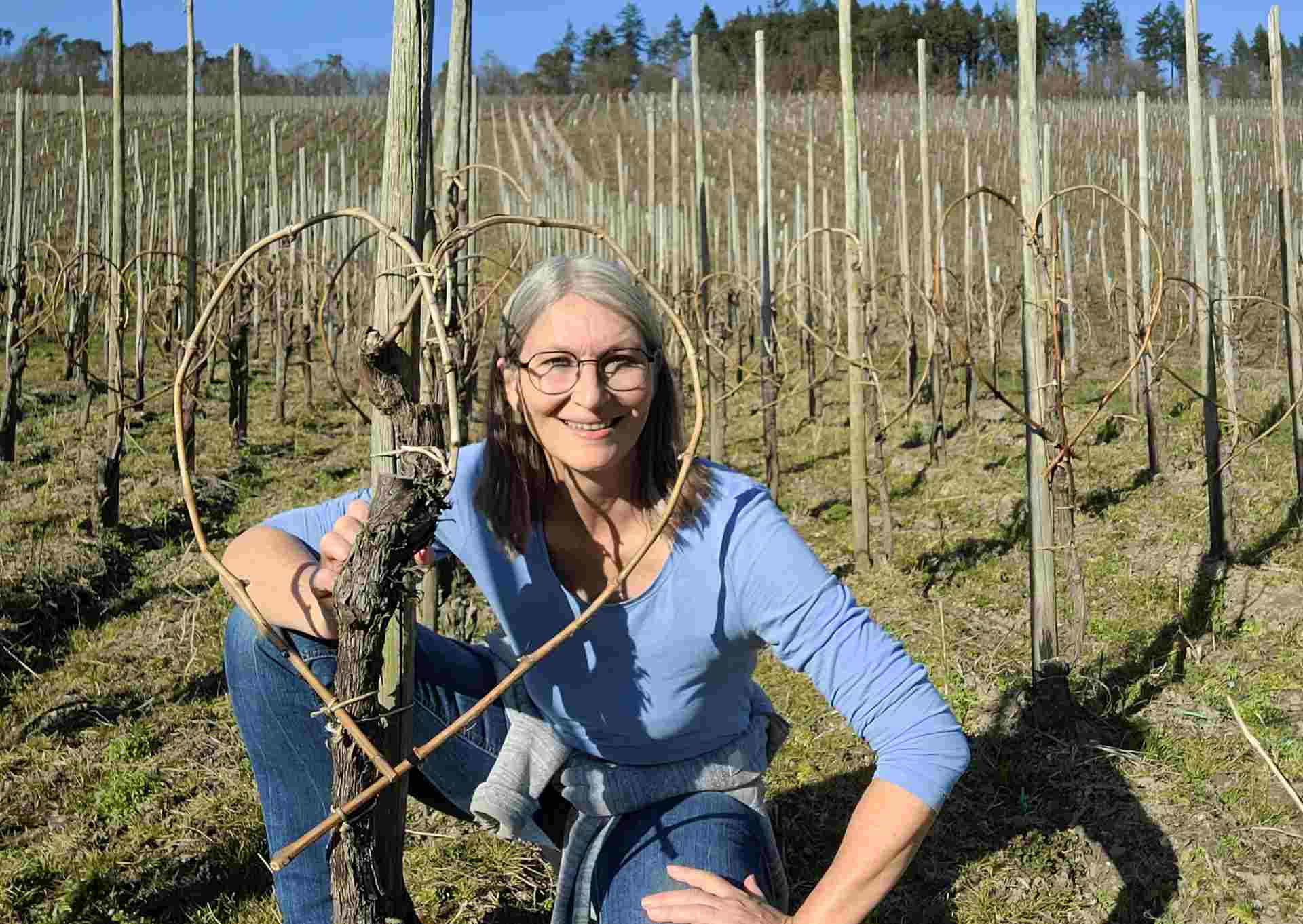 Frau schaut durch Herzrebe in einem Weinberg an der Mosel, März 2025