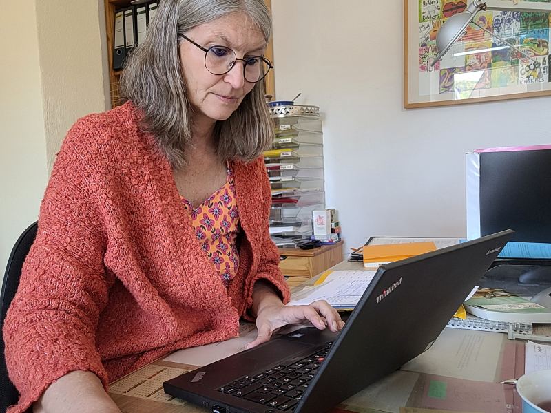 Frau an Schreibtisch arbeitet am Laptop