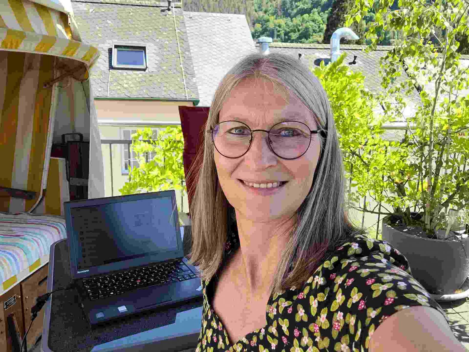Frau an Laptop auf dem Balkon