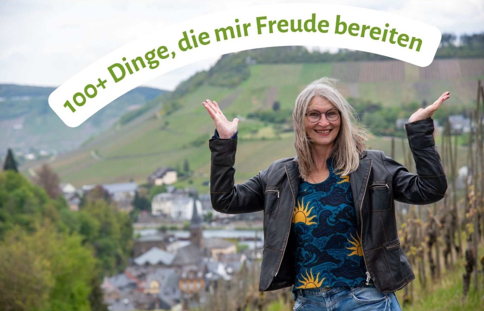 Frau hält ihre Handflächen nach oben und lacht, im Hintergrund Weinberge an der Mosel