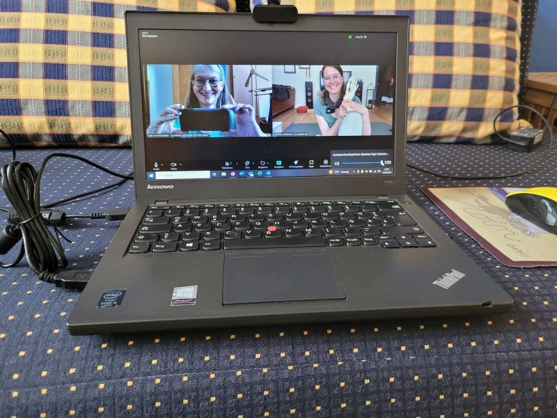 Zoom-Meeting auf einem Laptop, das auf einem Sofa steht