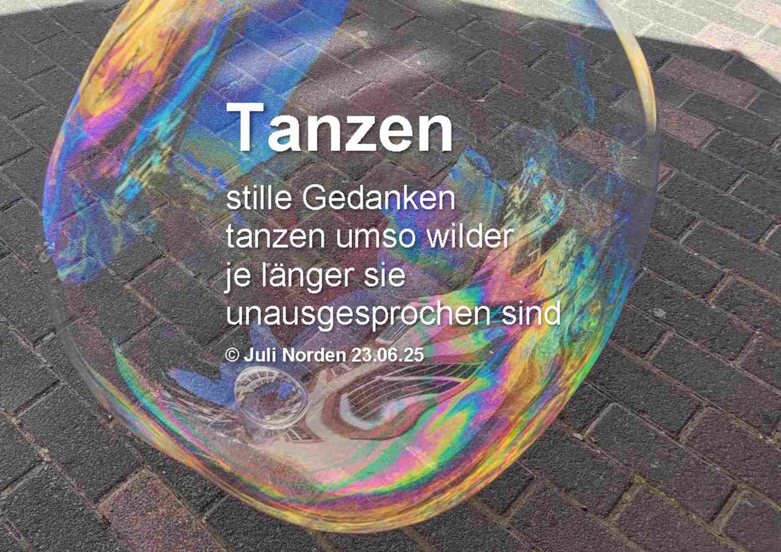 Eine große Seifenblase schwebt über einem Straßenpflaster, darauf das Gedicht "Tanzen" von Juli Norden: Tanzen/ stille Gedanken/ tanzen umso wilder/ je länger sie/ unausgesprochen sind/ (c) Juli Norden 23.06.25