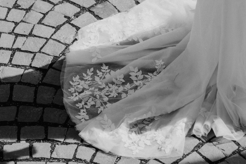 Schleppe eines  Brautkleides auf grauem Bodenpflaster.